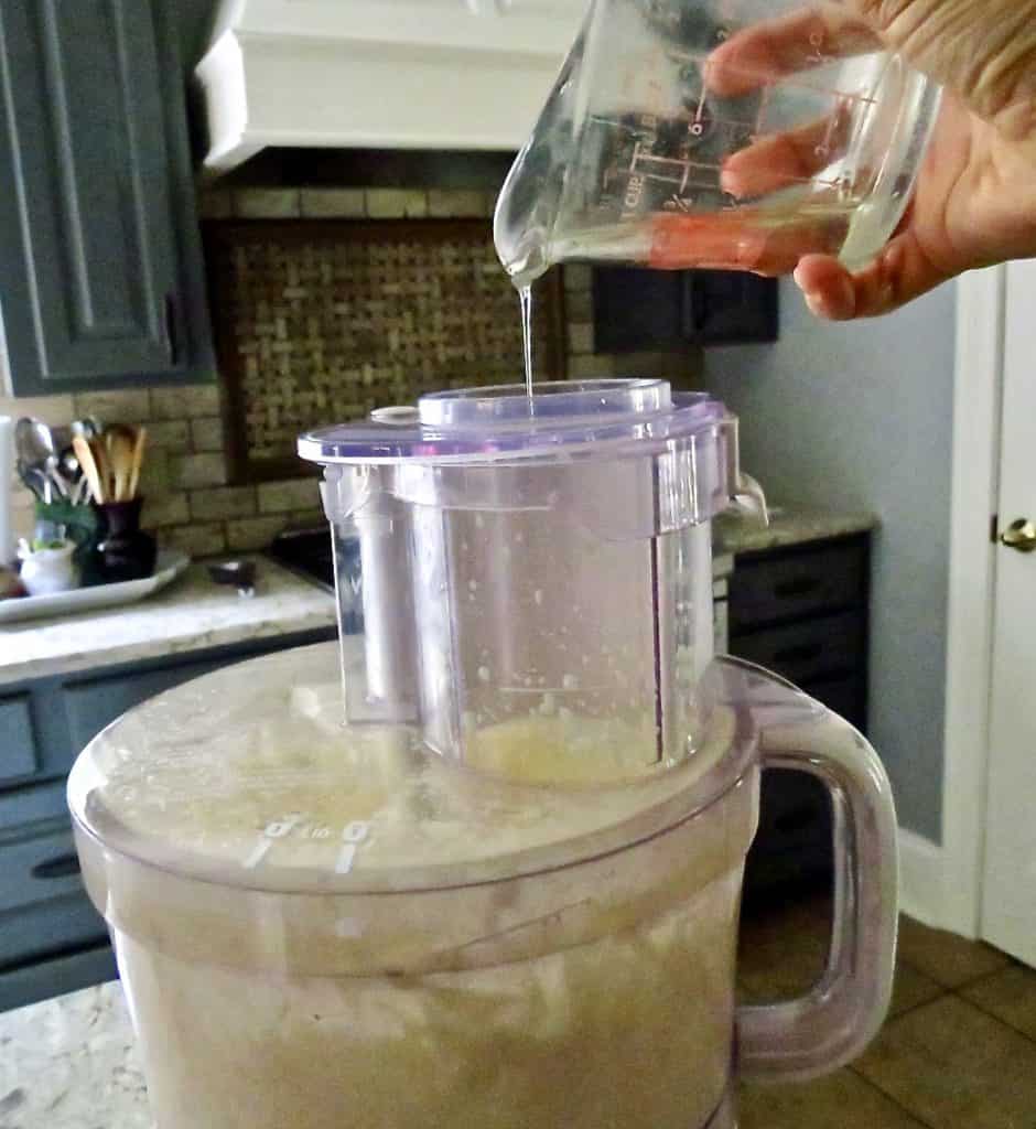 A food processor with oil added from the top.