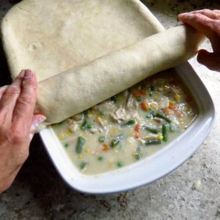 Rolling pie dough onto Chicken Pot Pie.