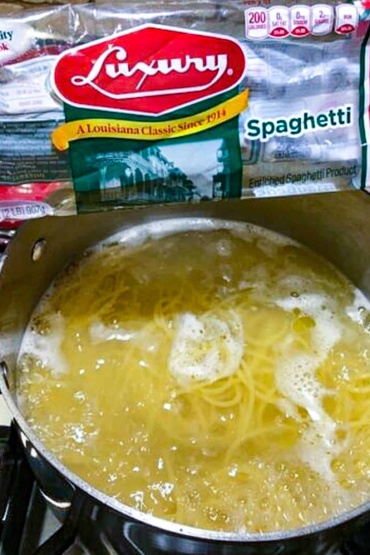 A bag of luxury spaghetti over a pot of cooked spaghetti.