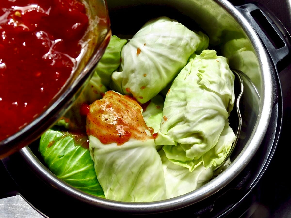 Classic Cabbage Rolls in the Instant Pot with tomato sauce being poured over them.