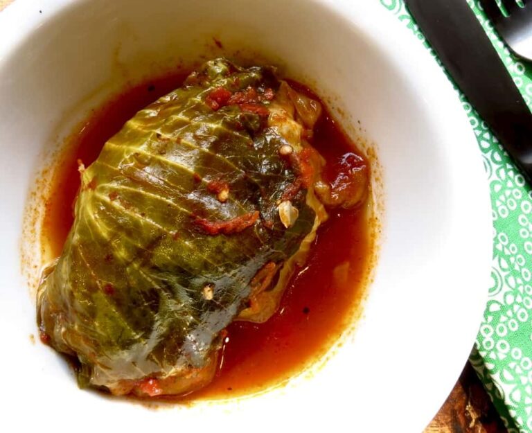 One Classic Cabbage Roll in a white plate in tomato sauce.