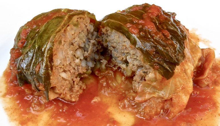 One Classic Cabbage Roll in a white plate in tomato sauce.