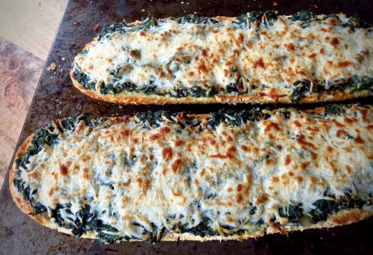 Two half loves of Spinach bread with cheese browned from the oven.