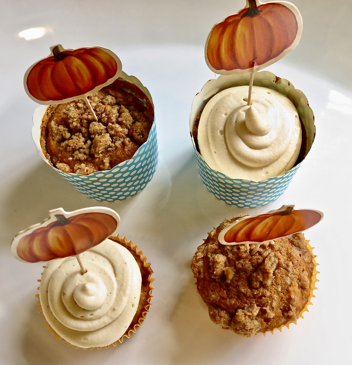Two pumpkin cupcakes and two Pumpkin Muffins With Streusel on a white tray.