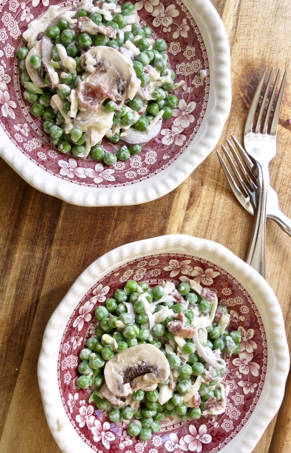 Pea Salad, The Forgotten Side Dish in 2 red and white toile bowls with forks on a wooden board.