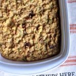 Cooked cornbread in a white casserole dish on an orange and white striped place mat.