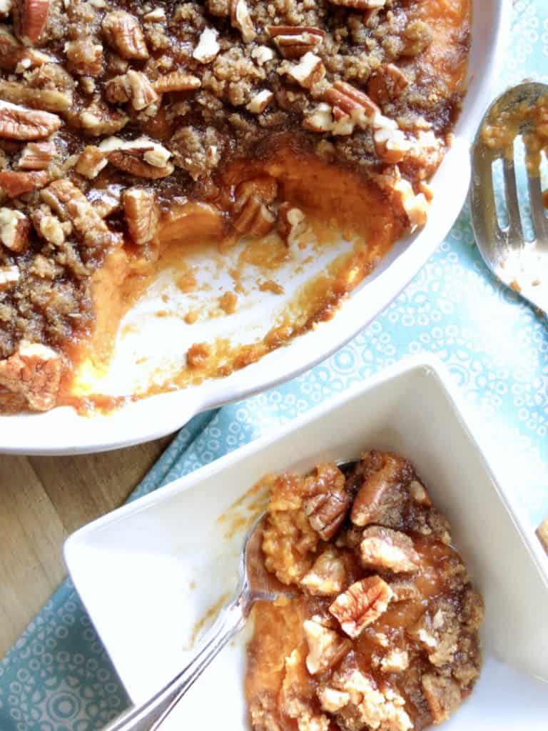 A casserole dish if Sweet Potato Casserole with a smaller dish with some sweet potato casserole in it.