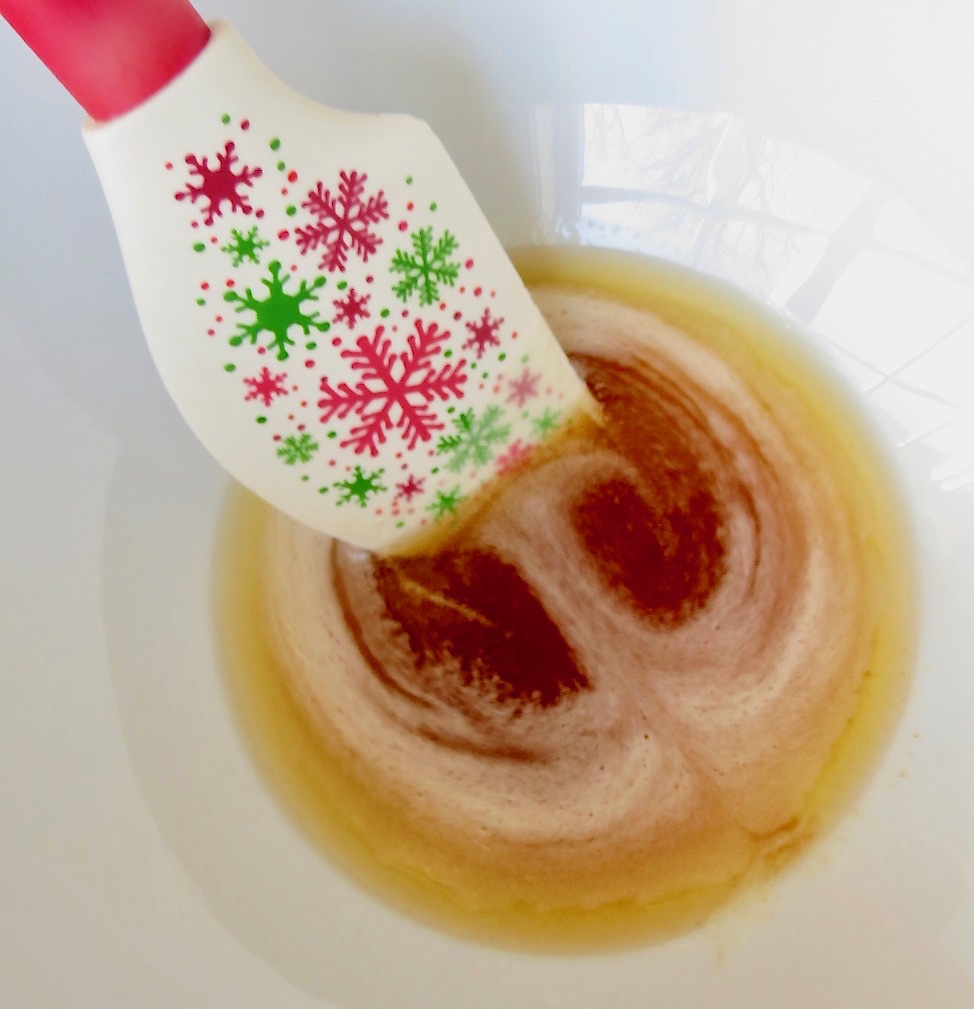 Red and white spatula stirring brown butter in a white bowl for Sugar Cookies.