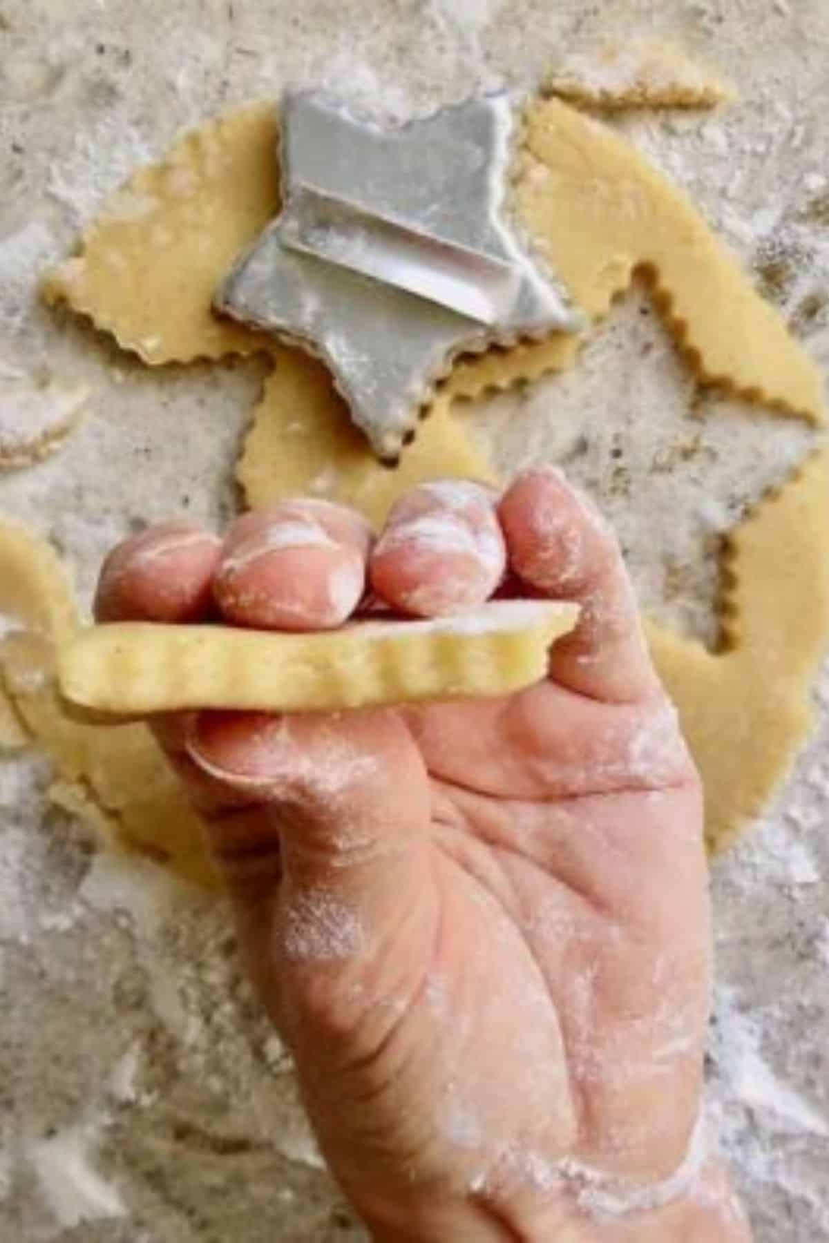 A hand holding a sugar cookie cut out into a star.