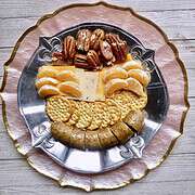 A silver plate with fleur de lis filled with boudin, crackers, cheeses, pecans, and orange slices for Easy Appetizers To Tease And Appease The Appetite.