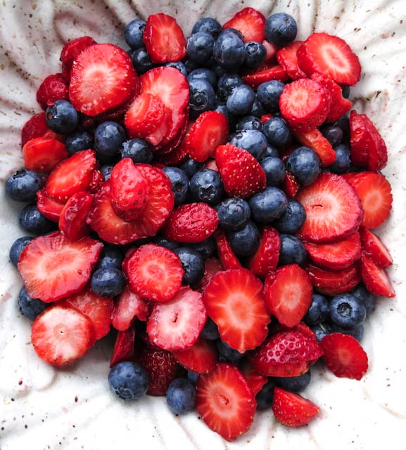 A bowl of sliced strawberries and blueberries for Keto Strawberry Jello Dessert.