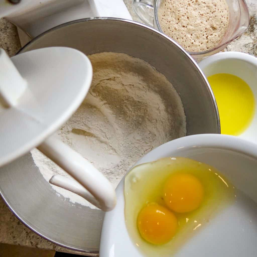 2 egg yolks being poured into flour mixture of Easy No-Knead Bread.