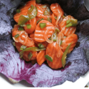 A bowl of sliced carrots and jalapeños on a bed of purple cabbage leaves.