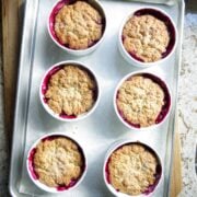 Six white ramekins filled with baked Easy Blueberry Pot Pie on a silver cookie sheet.