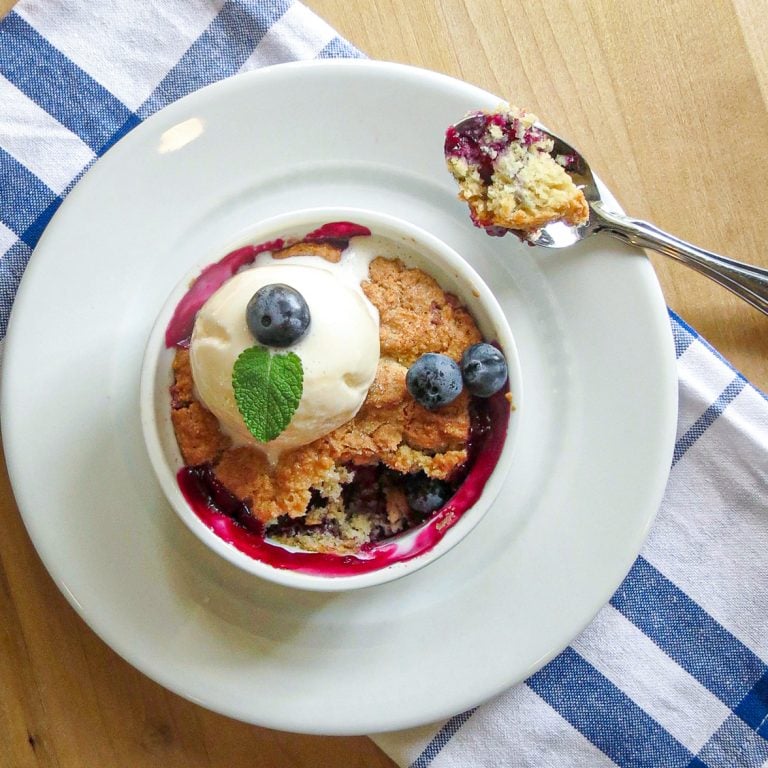 Easy Blueberry Pot Pie in a white ramekin bowl toped with ice cream next to a spoonful of pie.