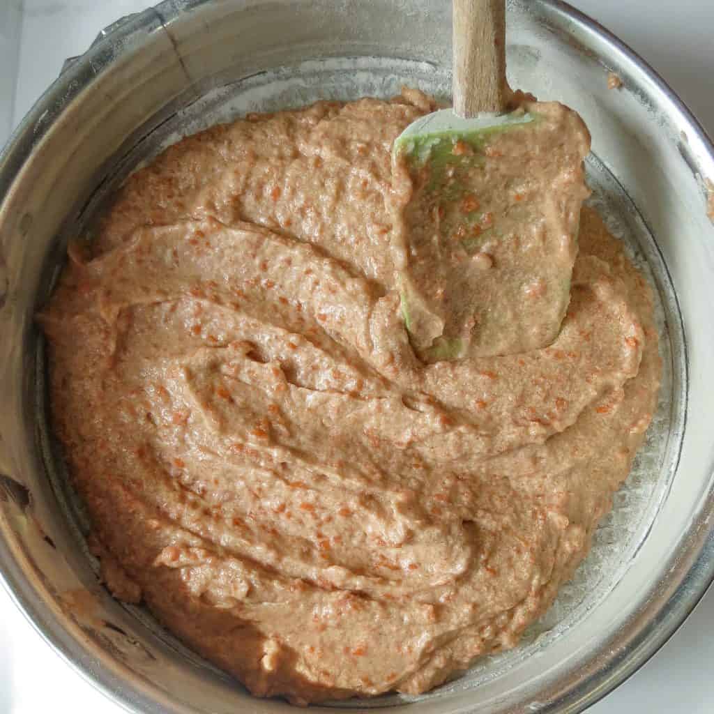 Spatula spreading Glazed Carrot Cake batter into a prepared springform pan.