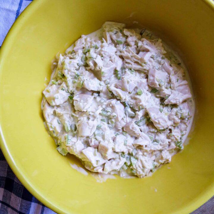 A yellow bowl of Classic Chicken Salad Your Way on a blue and whit cloth.