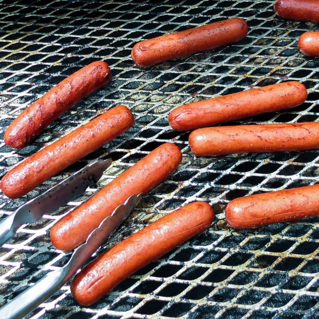 Weiners cooking on a grill.