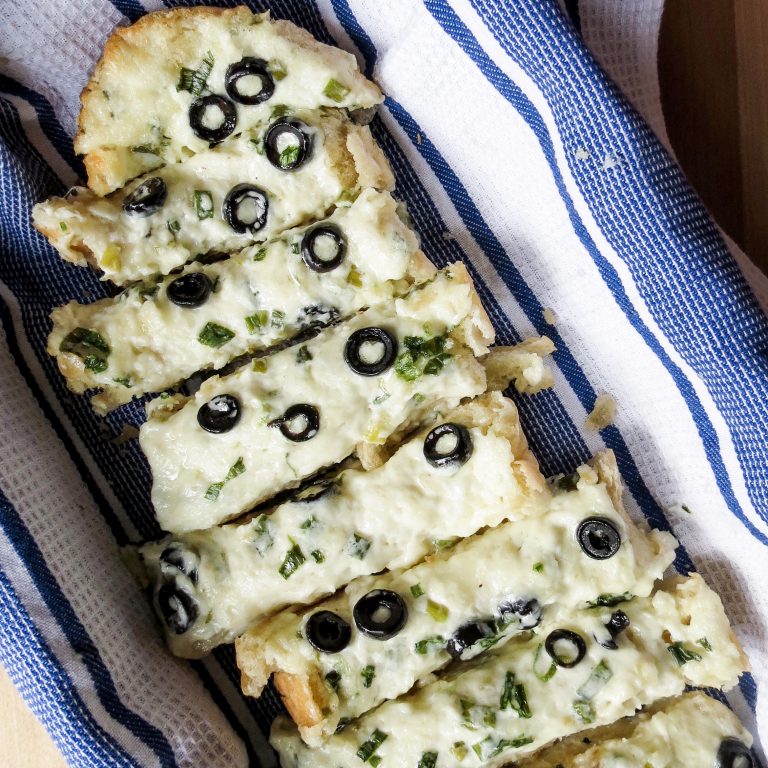 Slices of Cheesy Greek Bread on a blue and white dish towel.