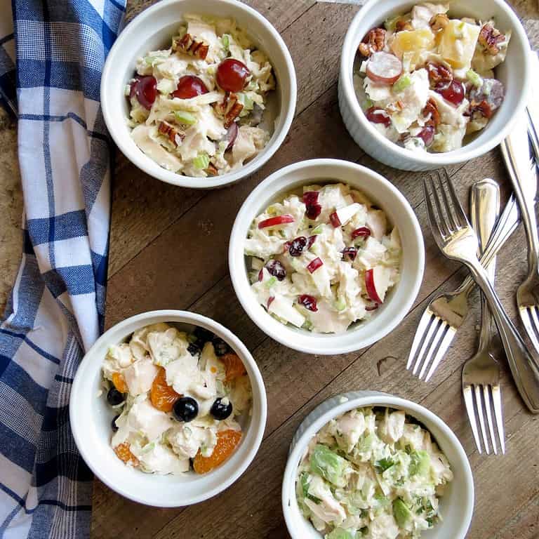 Five small white bowls on a wooden board of Chicken Salad Your Way.