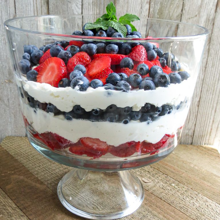 A glass trifle bowl filled with layers of Keto Lemon Berry Dessert.