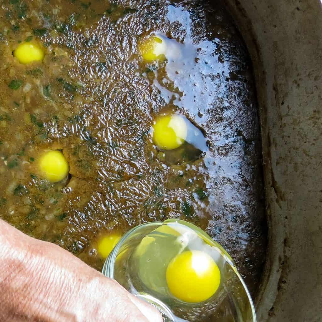 Fresh egg poured into a pot of gravy with eggs yolks sitting in the gravy for poaching.