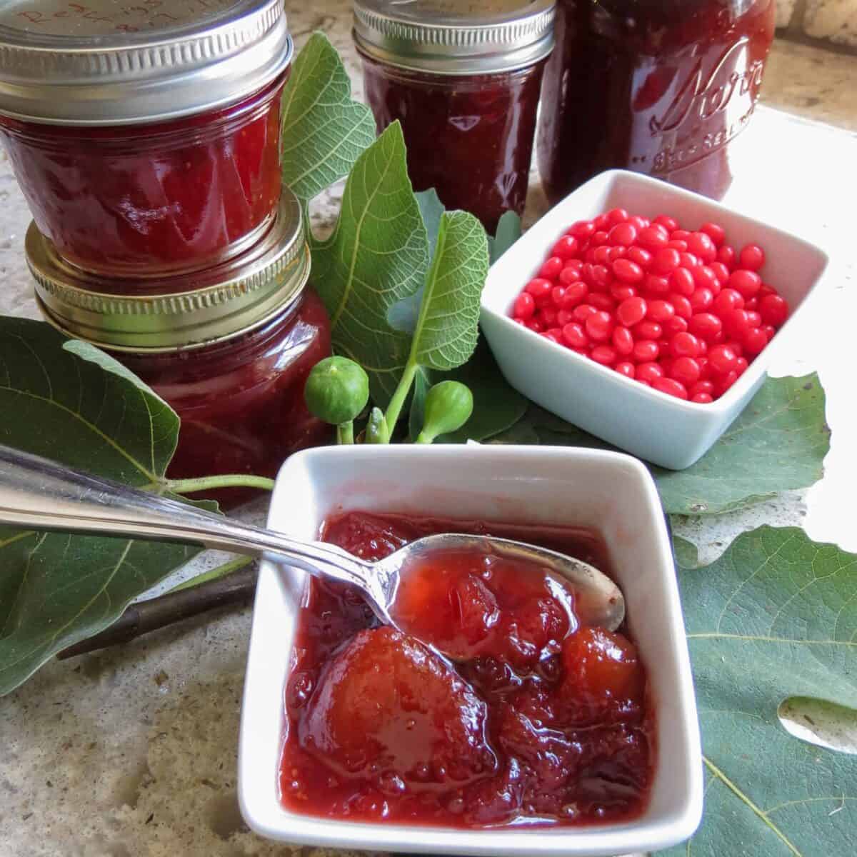 Bowls of fig jam and red hots with jars of fig jam.