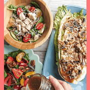 Dressing poured onto a fruit salad with a bowl of chicken salad and a plate of grilled greens and mushrooms.