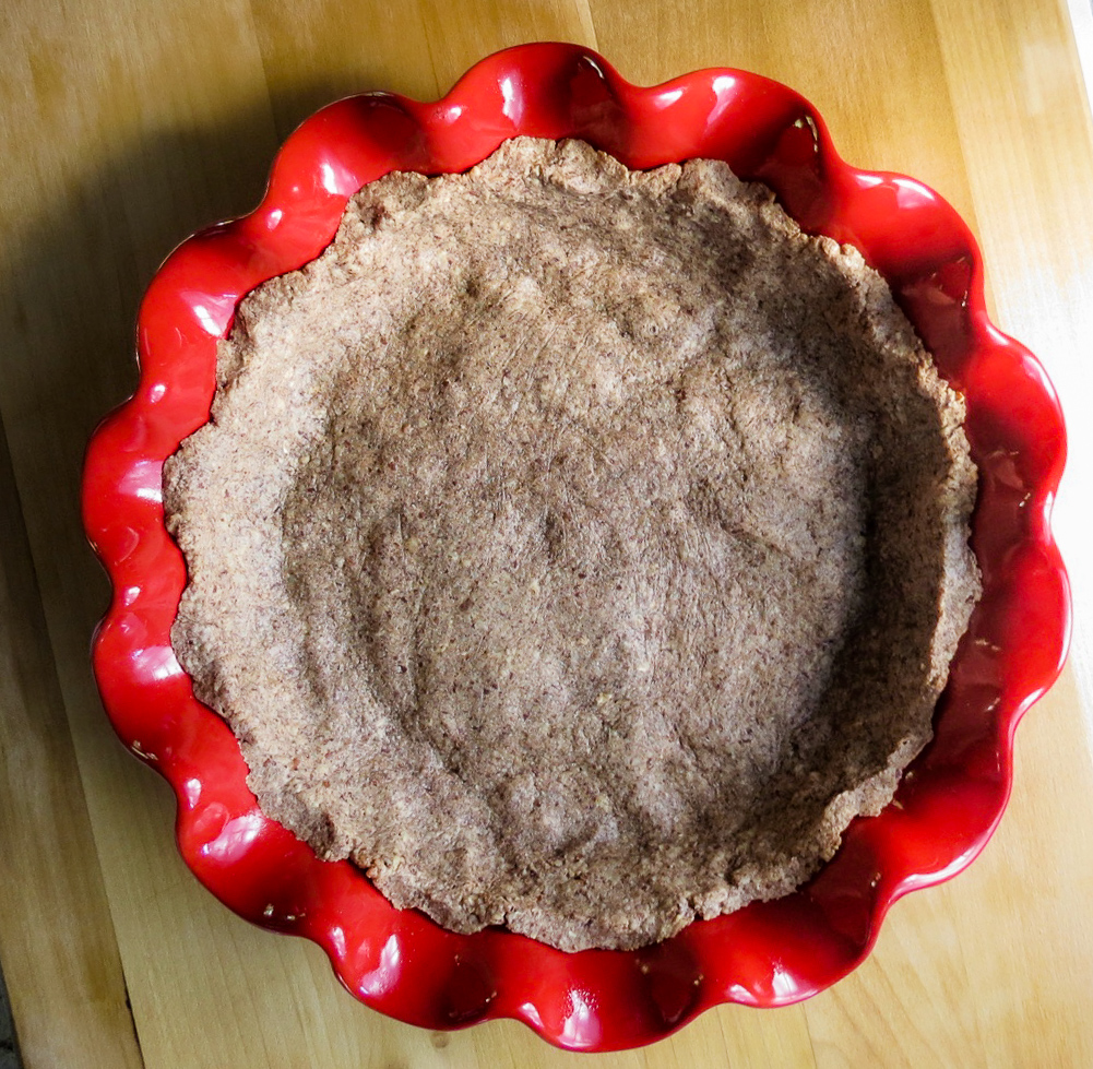A pecan crust in a red pie plate.