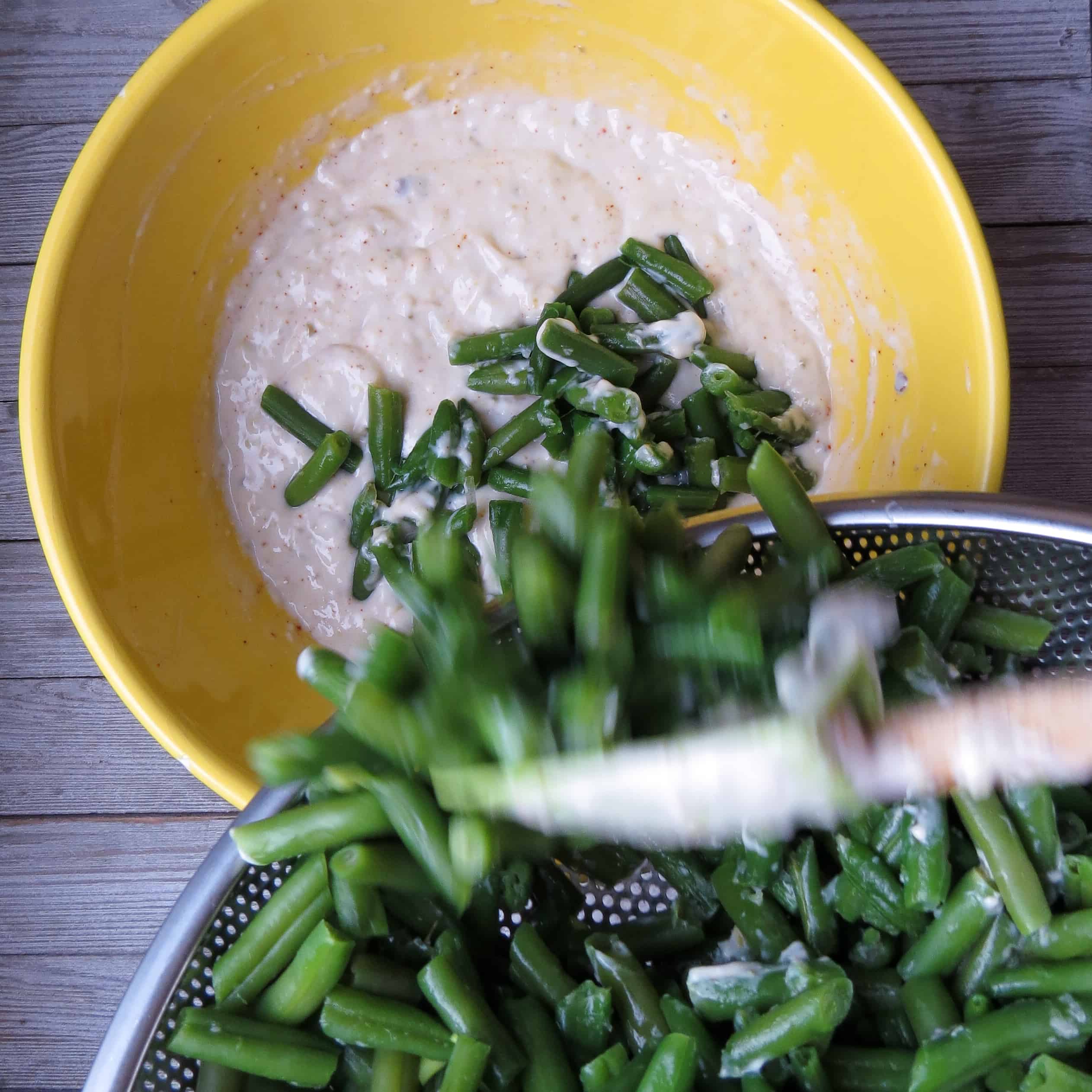Green beans spooned into a bowl of creamed mixture.