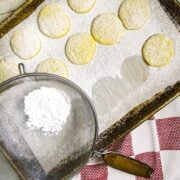 A cookie sheet of cooked cookies with powdered sugar.