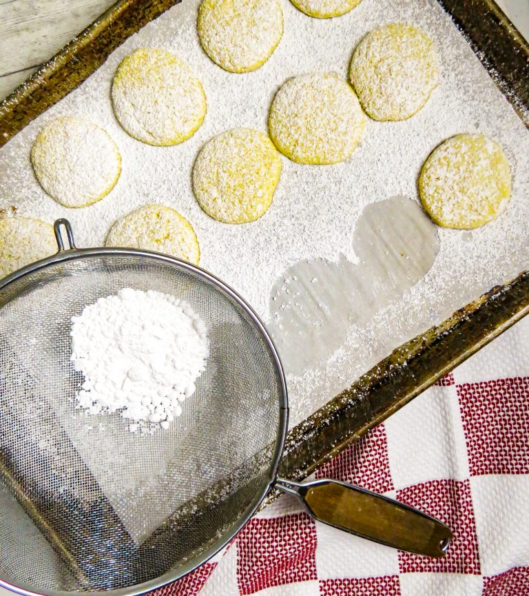 A cookie sheet of cooked cookies with powdered sugar.