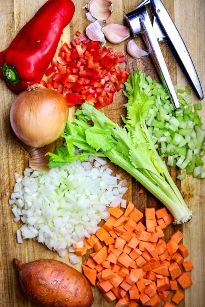 Fresh ingredients with cubed sweet potatoes on a cutting board.