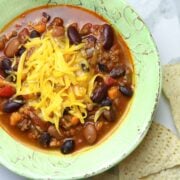 A bowl of chili topped with grated cheese.