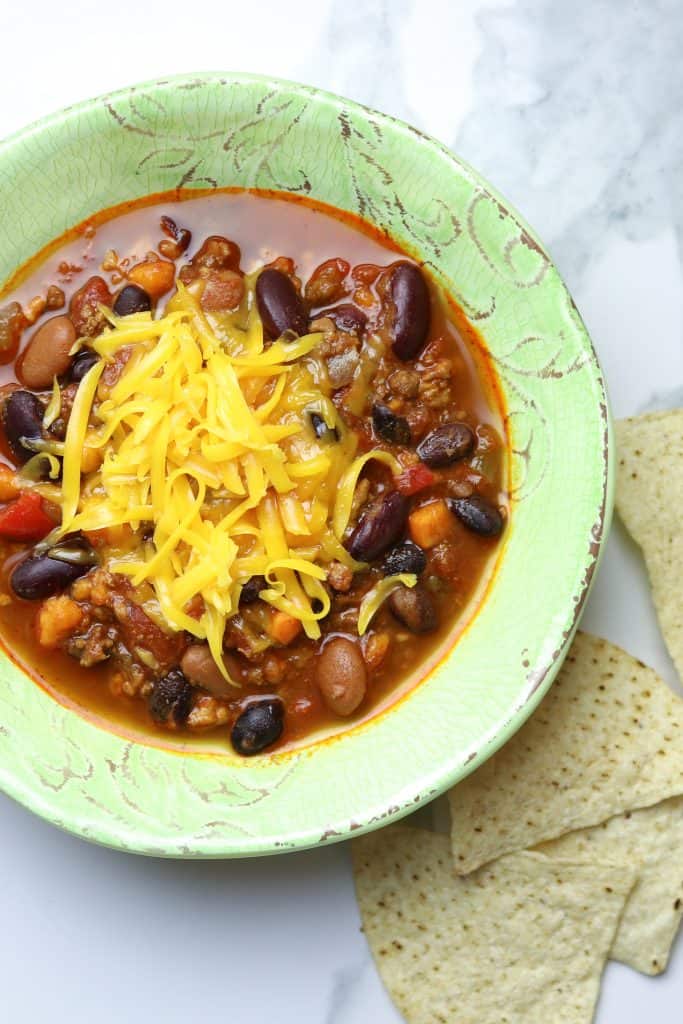 A bowl of chili topped with grated cheese.