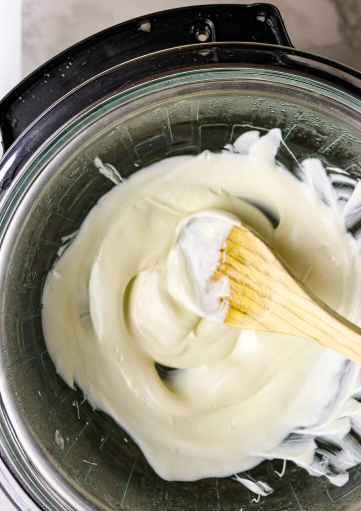 A wooden spoon stirring white almond bark.