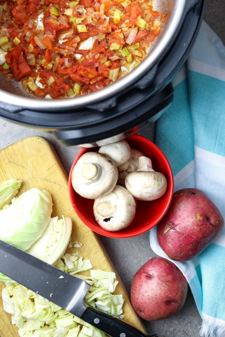 Chopped cabbage and other vegetables with a pot.