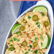 A dish of cheesy crawfish dip on top of tortilla chips with lime slices.