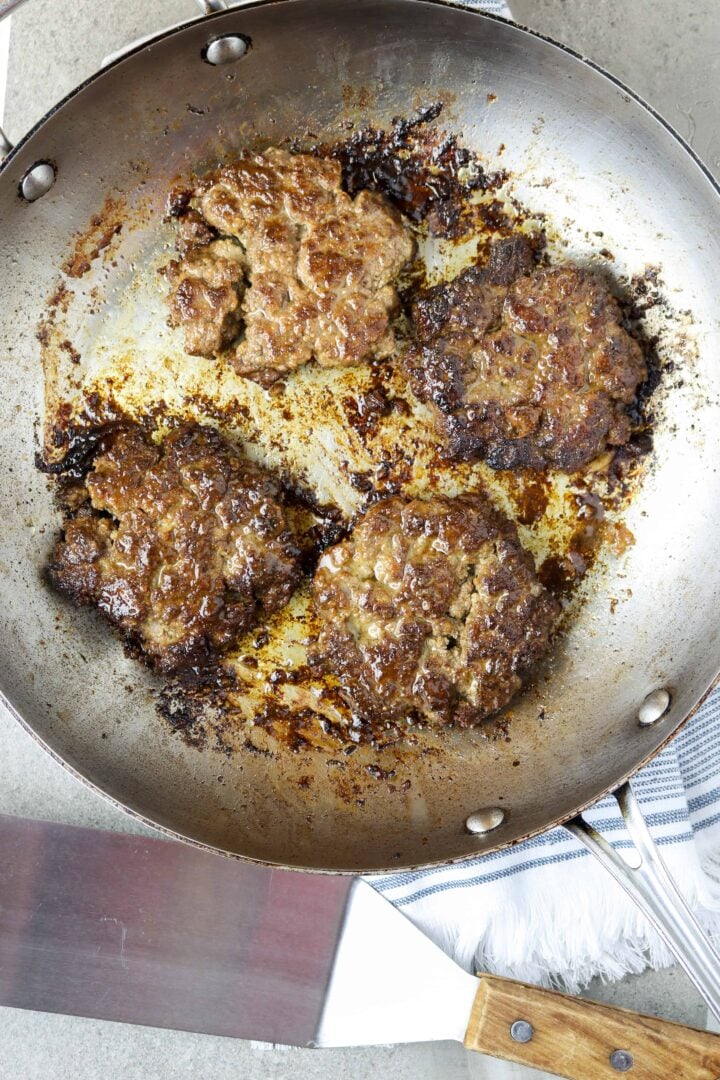 A pan of cooked hamburger patties.