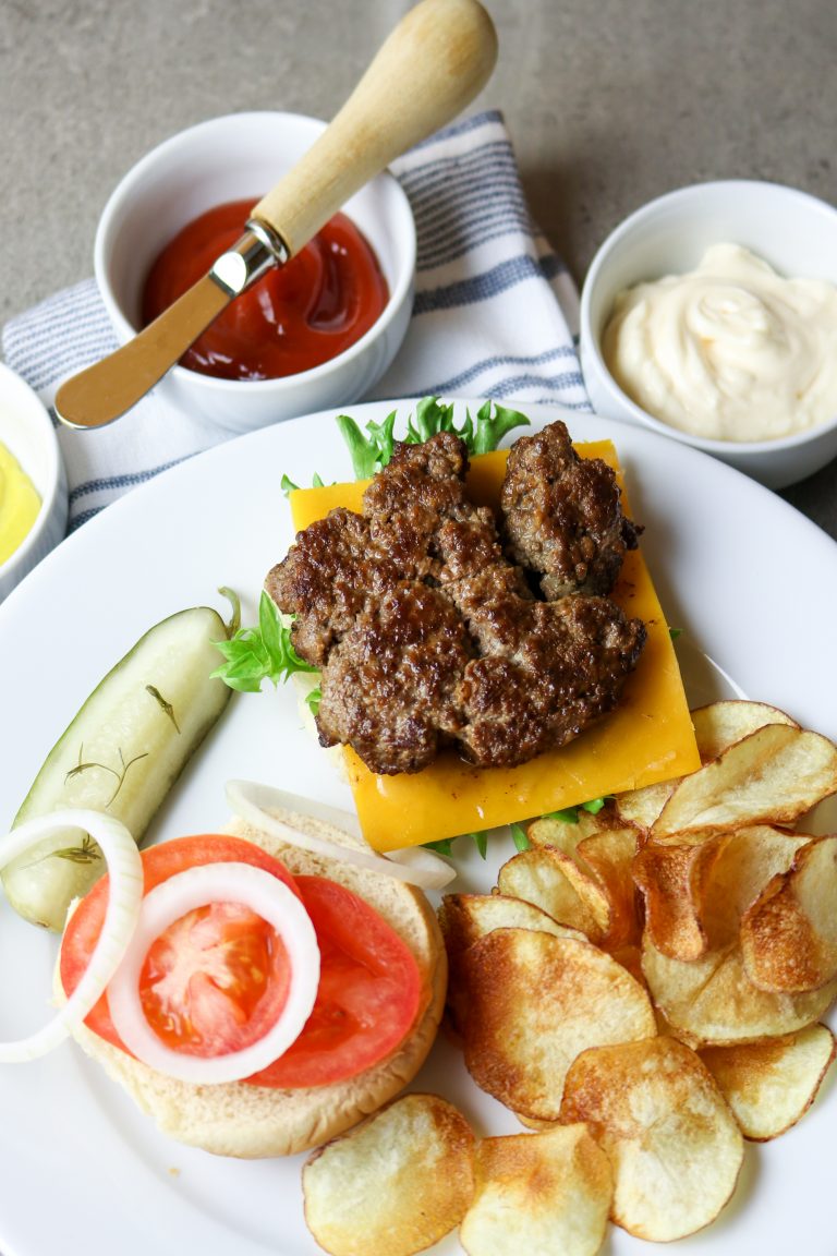 A white plate with an open faced Best Sizzle Burger Recipe and fries.
