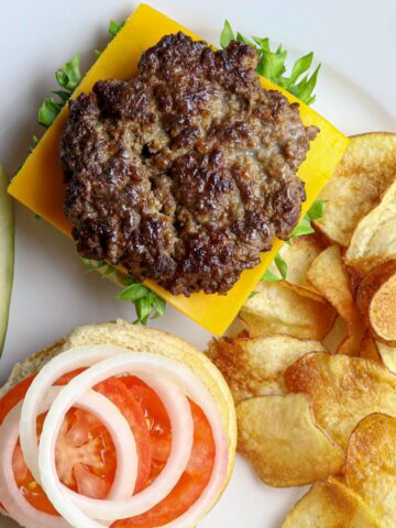A white plate with an open faced Best Sizzle Burger Recipe and fries.