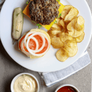 A white plate with an open faced Best Sizzle Burger Recipe and fries.