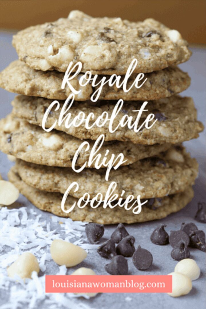 A stack of chocolate chip cookies with chocolate chips and coconut flakes beside it.