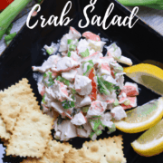 A plate of crab salad with a side of sliced lemons and crackers.