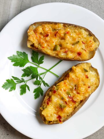 Two Twice-Baked Cheese Potato halves on a plate with parsley for garnish.