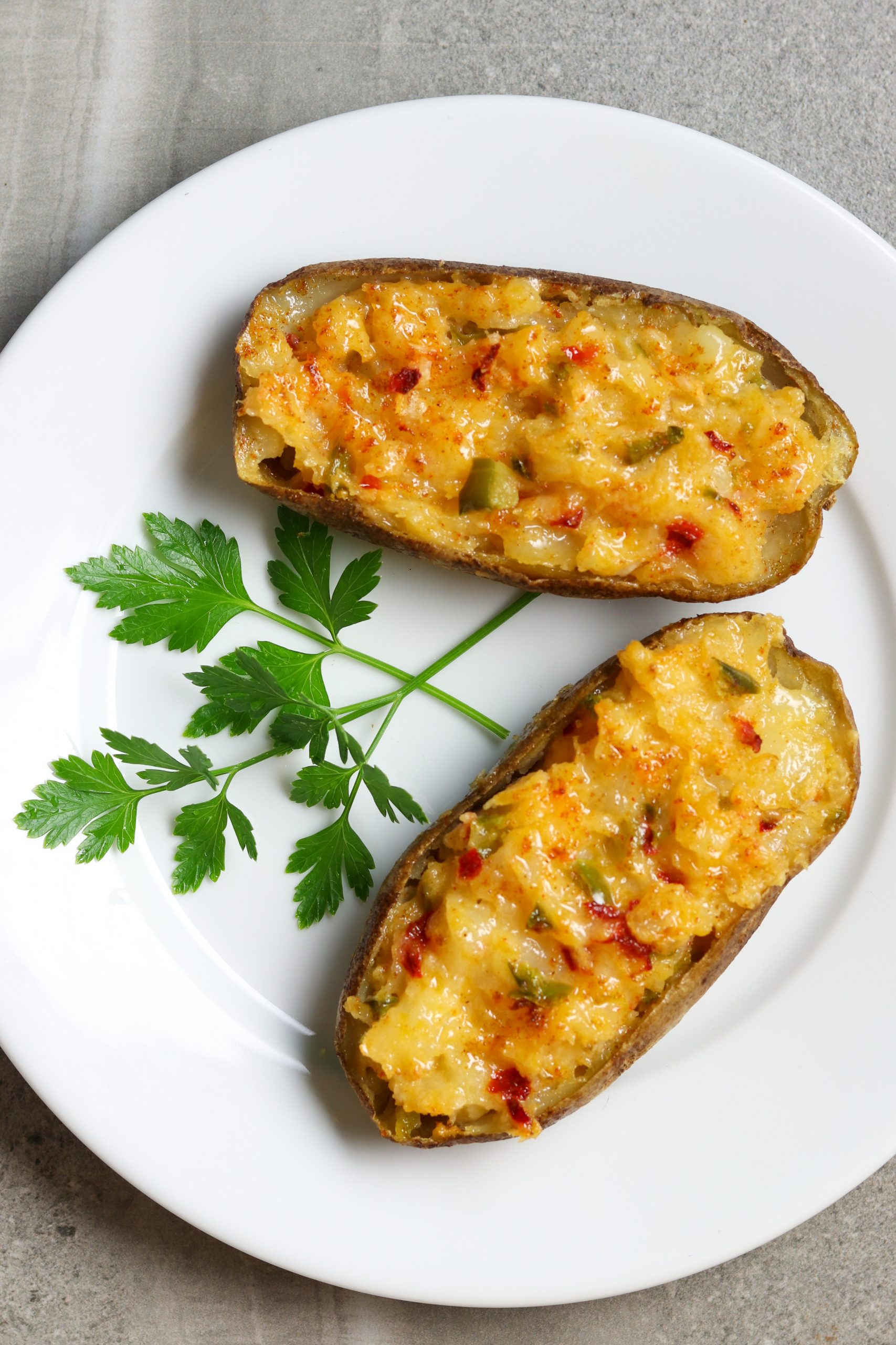 Two Twice-Baked Cheese Potato halves on a plate with parsley for garnish.