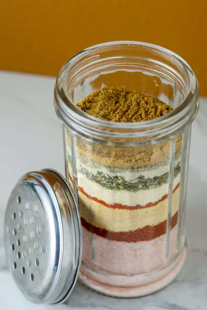 A glass container with layered with different spices.