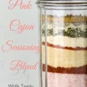 A glass shaker with layers of Cajun seasoning .