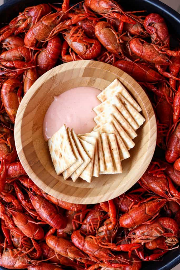 Bowl with dip and crackers in a pan of crawfish.