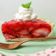 Slice of strawberry pie with a dollop of whipped cream on top.
